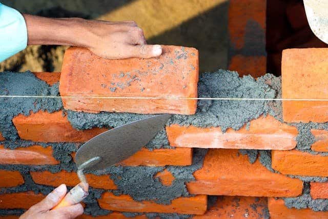 Mason worker constructing brick wall at construction site in Saudi Arabia